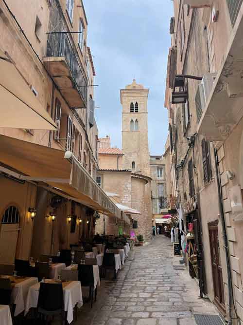 Ruelle pittoresque bordée de restaurants et clocher en pierre dans la vieille ville de Bonifacio, Corse