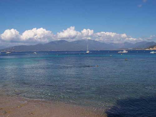 Plage de Campomoro avec eau turquoise et voiliers face aux montagnes corses