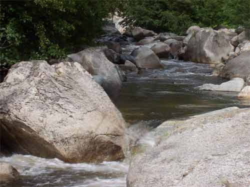 Vue des piscines naturelles de Zoza entre les rochers et la rivière