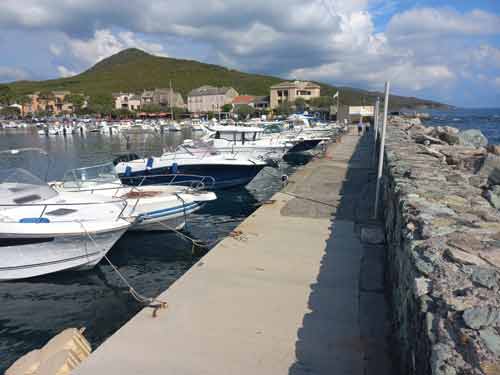 Jetée du port de Santa Severa avec vue sur les bateaux et les collines du Cap Corse
