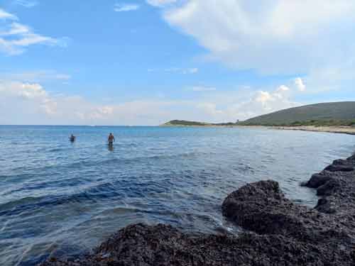 Baigneurs dans les eaux calmes de la plage de Barcaggio, au cœur d’un paysage sauvage du Cap Corse