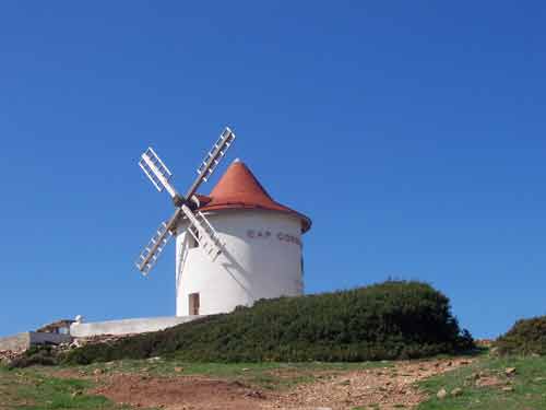 Moulin Mattei à toit rouge sous un ciel bleu intense, point de vue incontournable près de Centuri