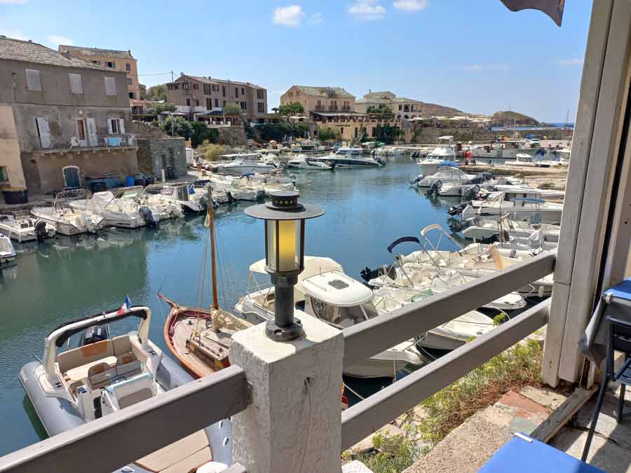Vue sur le port de Centuri et ses bateaux depuis la terrasse d'un restaurant, cadre idyllique du Cap Corse