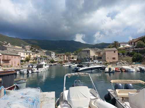 Bateaux amarrés dans le port de Centuri avec vue sur le village et les montagnes du Cap Corse