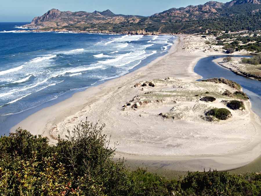 Plage d'Ostriconi avec dunes blanches et maquis sauvage en arrière-plan, à l'entrée du désert des Agriates