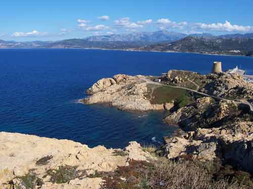 Vue panoramique sur les rochers de la Pietra et la tour génoise de L'Île-Rousse, avec les montagnes corses en arrière-plan