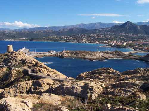 Vue sur L'Île-Rousse depuis la Pietra, entre mer turquoise, tour génoise et montagnes de Balagne