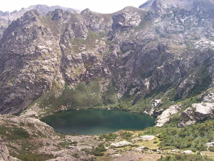 Vue aérienne du lac de Melo entouré de falaises verdoyantes, dans la haute vallée de la Restonica en Corse