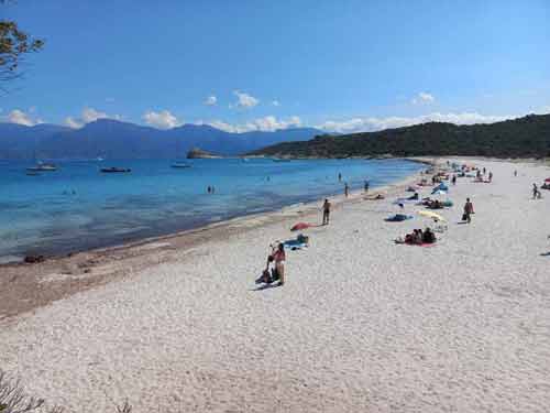 Plage du Loto dans le désert des Agriates avec sable blanc, baigneurs et bateaux au mouillage