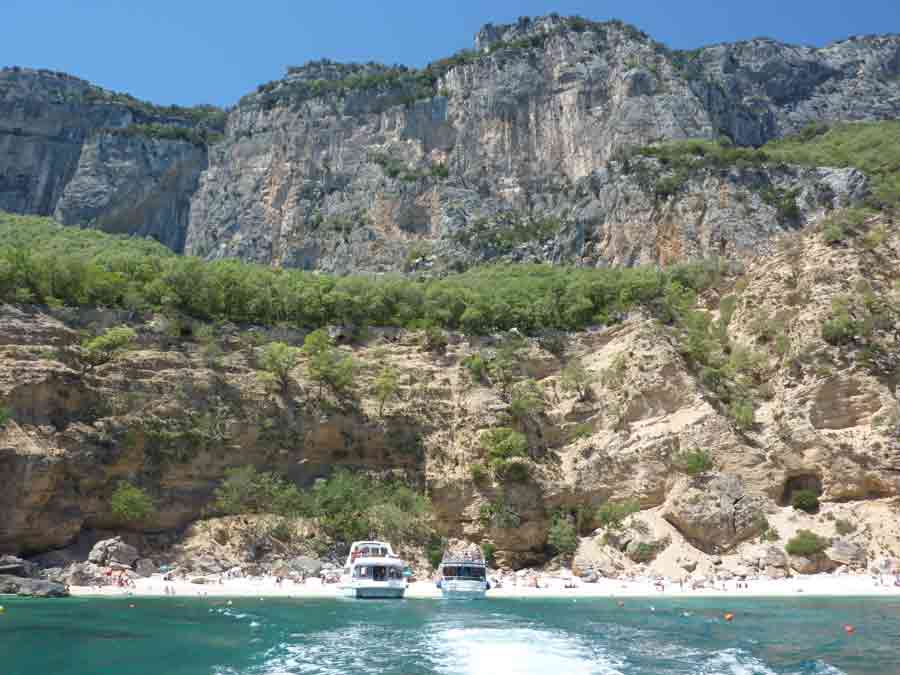 Vue sur les falaises calcaires et criques du golfe d’Orosei avec des bateaux amarrés