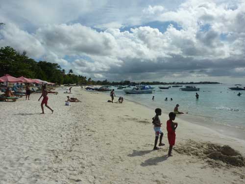 Jeunes enfants jouant sur la plage animée de Trou-aux-Biches, face à une mer turquoise propice à la baignade et au snorkeling