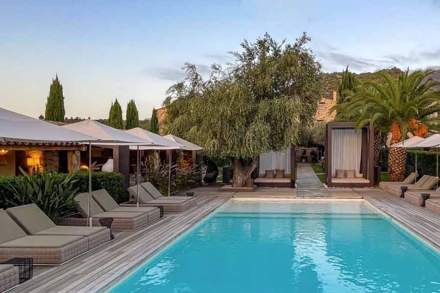 Piscine extérieure élégante entourée de transats et palmiers à l’Hôtel La Dimora & Spa à Saint-Florent en Corse (hotel spa corse)