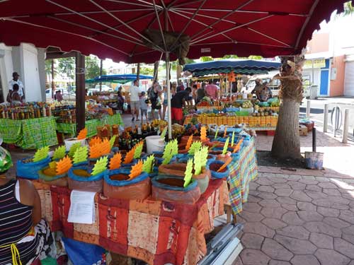 Étals d’épices et de rhums arrangés sous des parasols rouges au marché de Saint-François en Guadeloupe