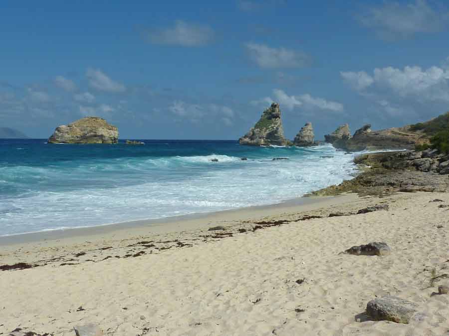 Plage sauvage de la Pointe des Châteaux en Guadeloupe avec formations rocheuses en arrière-plan
