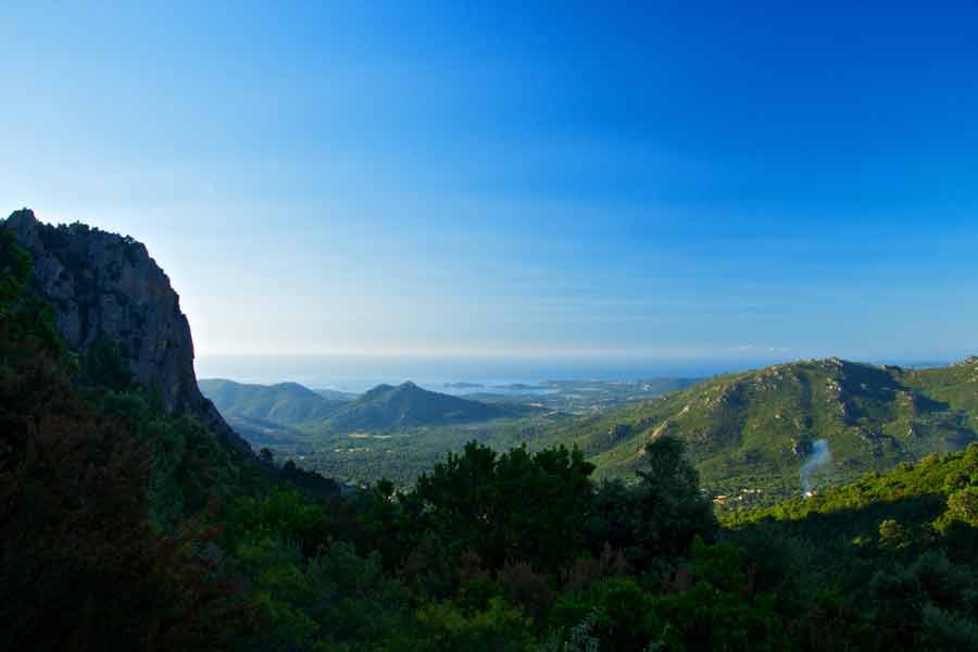 Vue panoramique sur les montagnes du GR20 entre Conca et Paliri, avec la mer Méditerranée au loin sous le ciel bleu de Corse