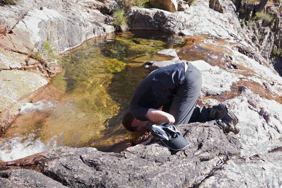 Randonneur se désaltérant dans un ruisseau de montagne sur le GR20 entre Conca et Paliri, lors de la première étape en Corse