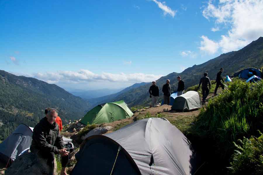 Campement de randonneurs au refuge d’Asinau sur le GR20 sud, avec vue sur les montagnes corses en fin d'après-midi
