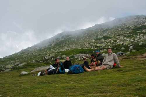 Groupe de randonneurs en pause sur une prairie d’altitude du GR20, entouré de brume et de rochers près du col de Verde en Corse
