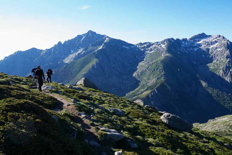 Randonneurs progressant sur le GR20 face aux sommets enneigés entre L’Onda et Petra Piana, en Corse