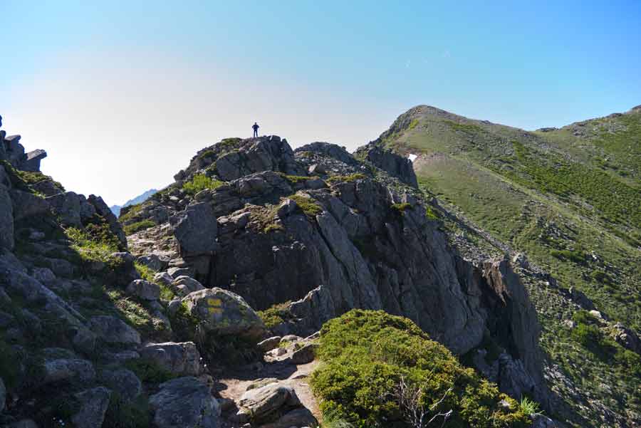 Randonneur solitaire sur une arête rocheuse du GR20 entre L’Onda et Petra Piana, au cœur des montagnes corses