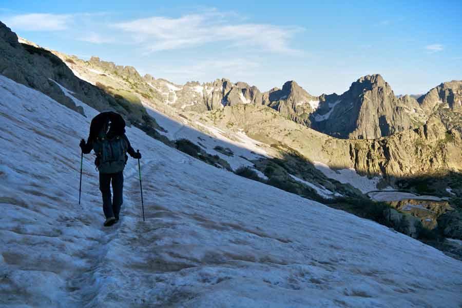 Randonneur traversant un névé sur le GR20 entre Petra Piana et Manganu, dans les montagnes corses