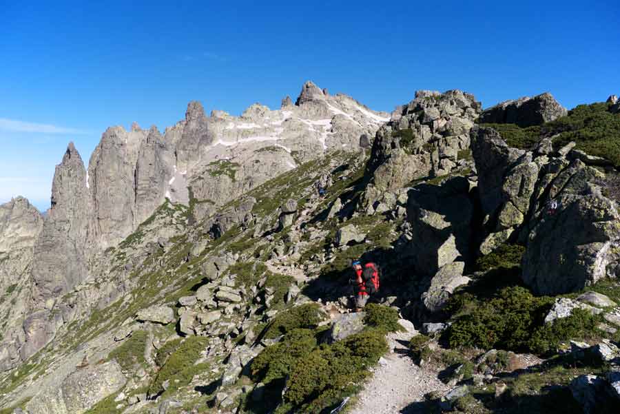 Randonneur sur le sentier rocailleux du GR20 entre Petra Piana et Manganu, entourés de pics acérés corses