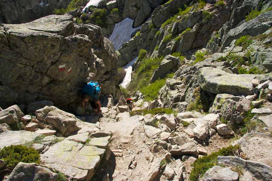 Randonneur escaladant un passage rocheux sur le GR20 entre Petra Piana et Manganu, dans les montagnes corses