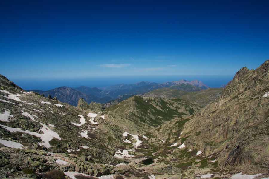 Paysage alpin du GR20 entre Petra Piana et Manganu, avec vue sur les montagnes corses et la mer au loin