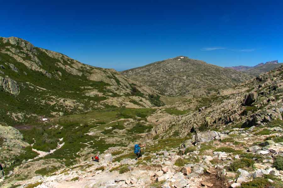 Randonneurs sur le GR20 descendant vers la vallée entre Petra Piana et Manganu, au cœur des montagnes corses