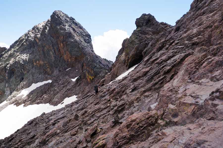 Randonneur progressant sur les flancs rocheux du Monte Cinto sur le GR20 en Corse
