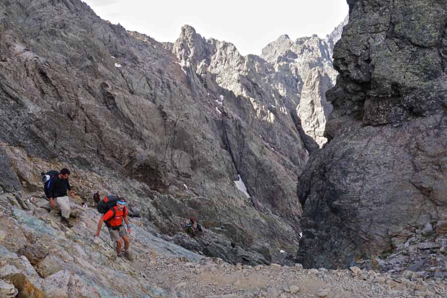 Randonneurs sur le GR20 dans le cirque de la Solitude en Corse, entre les parois rocheuses du massif du Monte Cintu