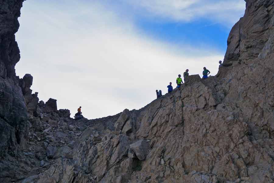 Randonneurs progressant sur les crêtes du GR20 dans le cirque de la Solitude, face au ciel corse