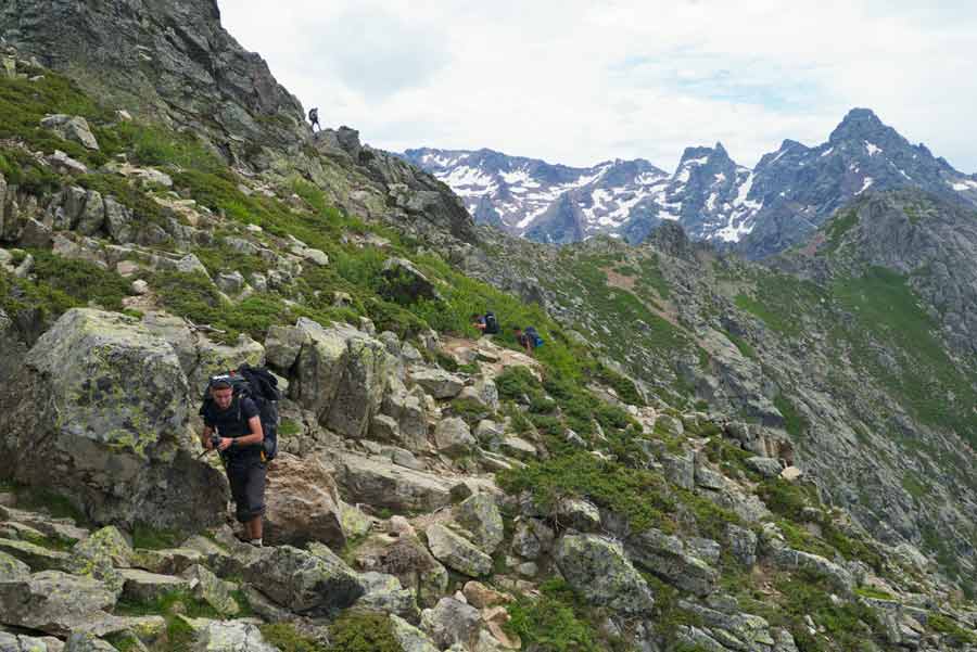 Montée entre Tighjettu et Caruzzu sur le GR20 avec vue sur les sommets enneigés du Monte Cintu en Corse