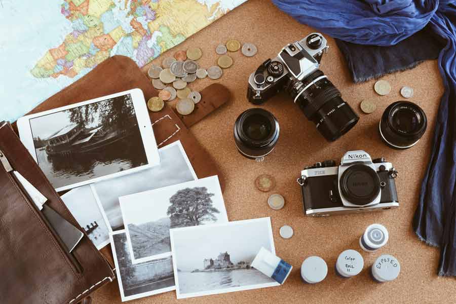 Matériel photographique et carnets de voyage disposés avant le départ, illustrant la préparation d’un séjour photo
