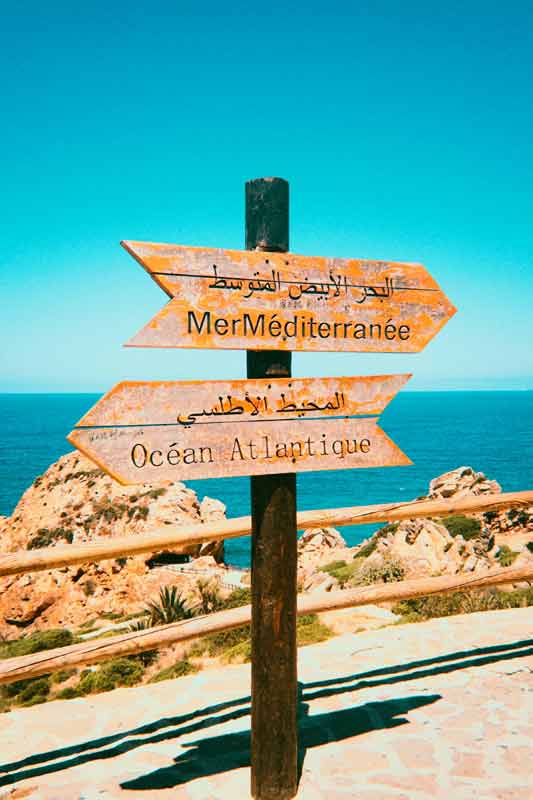 Panneau directionnel entre la mer Méditerranée et l’océan Atlantique, symbole de carrefour culturel et de choix de voyage