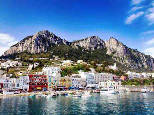 Destination med à Capri en Italie, port méditerranéen aux maisons colorées nichées au pied de falaises calcaires face à la mer