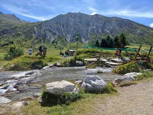 Paysage de montagne à Tignes en France, ruisseau alpin et sentier de randonnée illustrant l’esprit du voyage lent et authentique de destination med