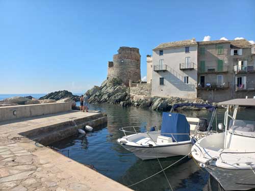 Le petit port d'Erbalunga avec ses barques amarrées face aux maisons ocre et à la tour génoise, Cap Corse