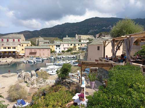 Le port de Centuri vu depuis les hauteurs, avec ses maisons roses et jaunes serrées autour du mouillage