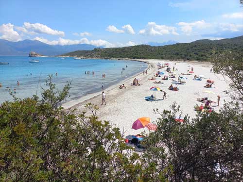 Vue plongeante sur la plage de Lodo, sa foule estivale et son eau turquoise cernée de maquis, dans le désert des Agriates