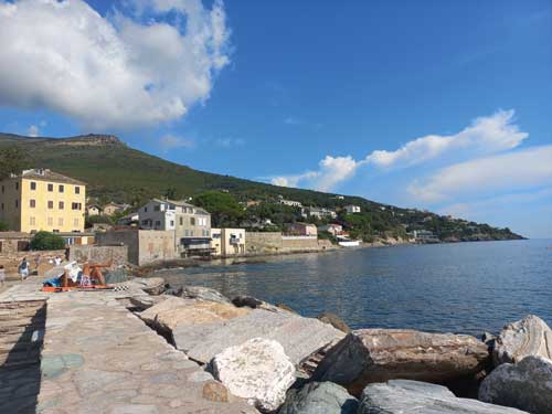 La côte du Cap Corse depuis les rochers d'Erbalunga, avec le village et ses collines verdoyantes en arrière-plan
