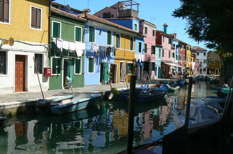 Maisons colorées de Burano près de Venise en Italie, canal avec barques amarrées et linge séché aux fenêtres, ambiance authentique pour un voyage de noces