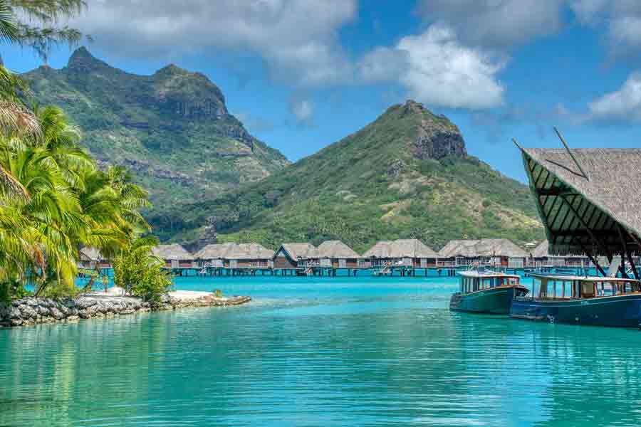 Lagon turquoise de Bora-Bora en Polynésie française, bungalows sur pilotis face aux montagnes verdoyantes, destination emblématique du voyage de noces