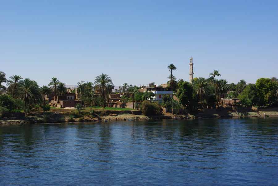 Village égyptien bordé de palmiers et de son minaret, aperçu depuis le pont du bateau lors de notre croisière sur le Nil entre Louxor et Assouan