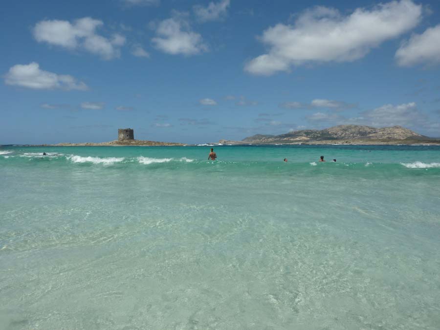 Baigneurs dans les eaux turquoise de la plage de La Pelosa à Stintino, face à la tour aragonaise et à l'île de l'Asinara