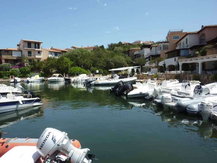 Bateaux pneumatiques amarrés dans une marina de Porto Cervo, bordée de villas aux tons ocre de la Costa Smeralda